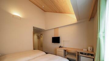 Una habitación de hotel con cama, escritorio, televisor y zona de ducha.