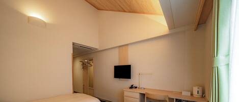 Une chambre d’hôtel équipée d’un lit, d’un bureau, d’une télévision et d’un espace douche.