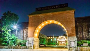 Un arco de ladrillo con un cartel que dice "Kurashiki-Ivy Square" que conduce a un edificio con entrada de cristal.