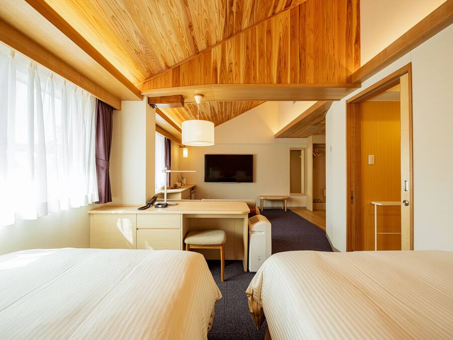 Una habitación de hotel con dos camas, un escritorio, una silla, un televisor y un armario.