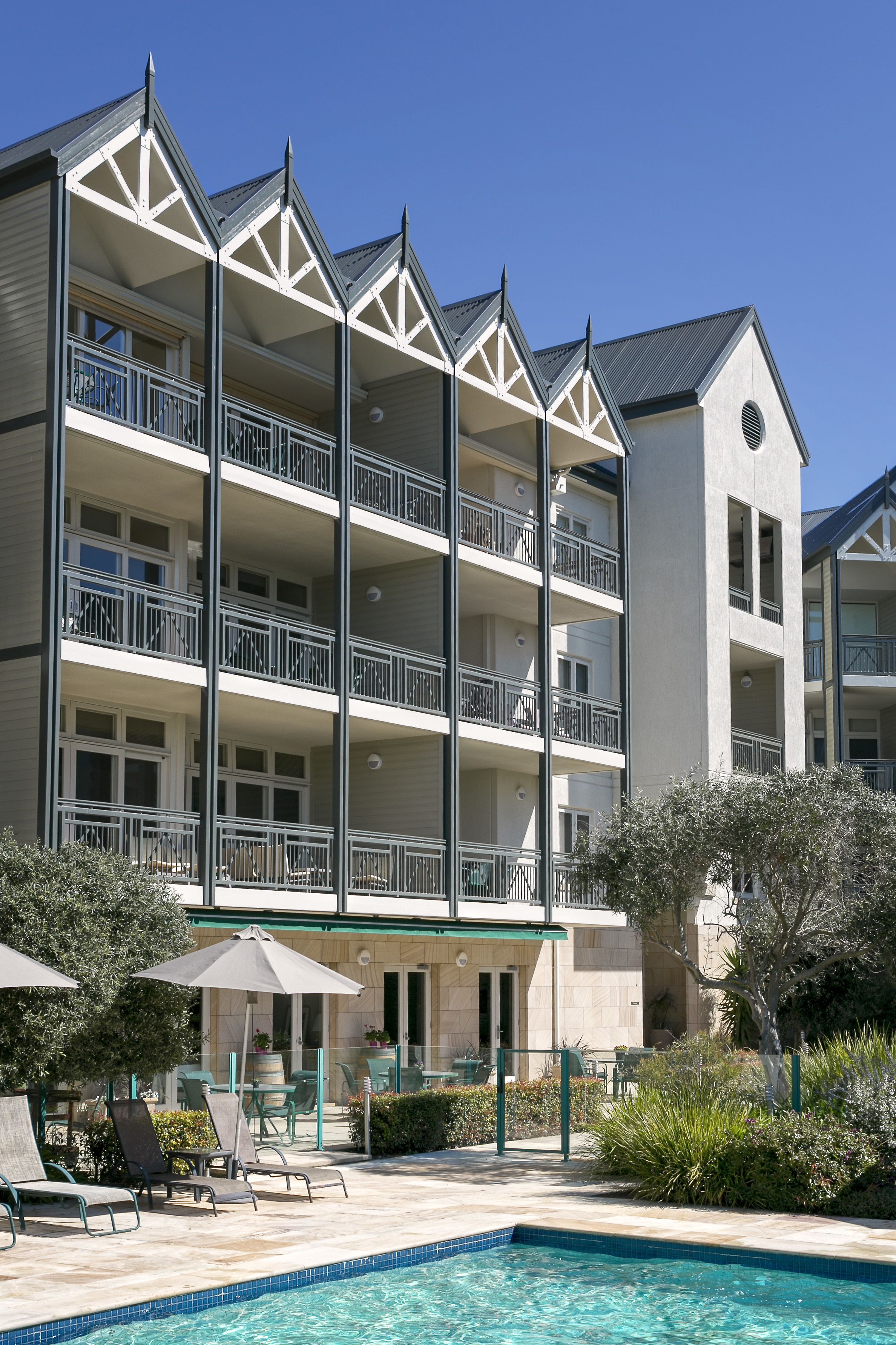 A multi-story hotel with balconies, a swimming pool, and outdoor seating.