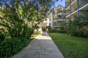 A pathway leading to a building with multiple balconies and a well-maintained garden. - Portsea Village Resort (Portsea)