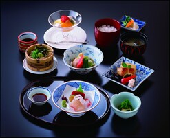 Variedad de platos japoneses, entre ellos sushi, sashimi y tempura, servidos en cerámica y cristalería tradicionales.