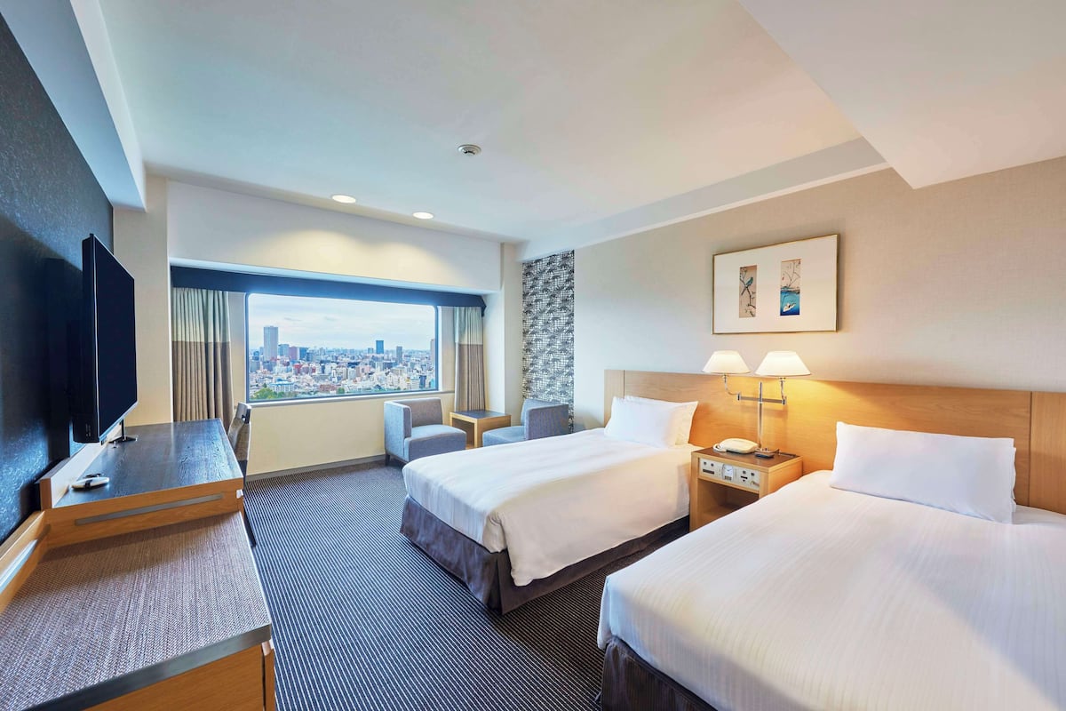Une chambre d’hôtel avec deux lits, un bureau, une télévision et une vue sur la ville.