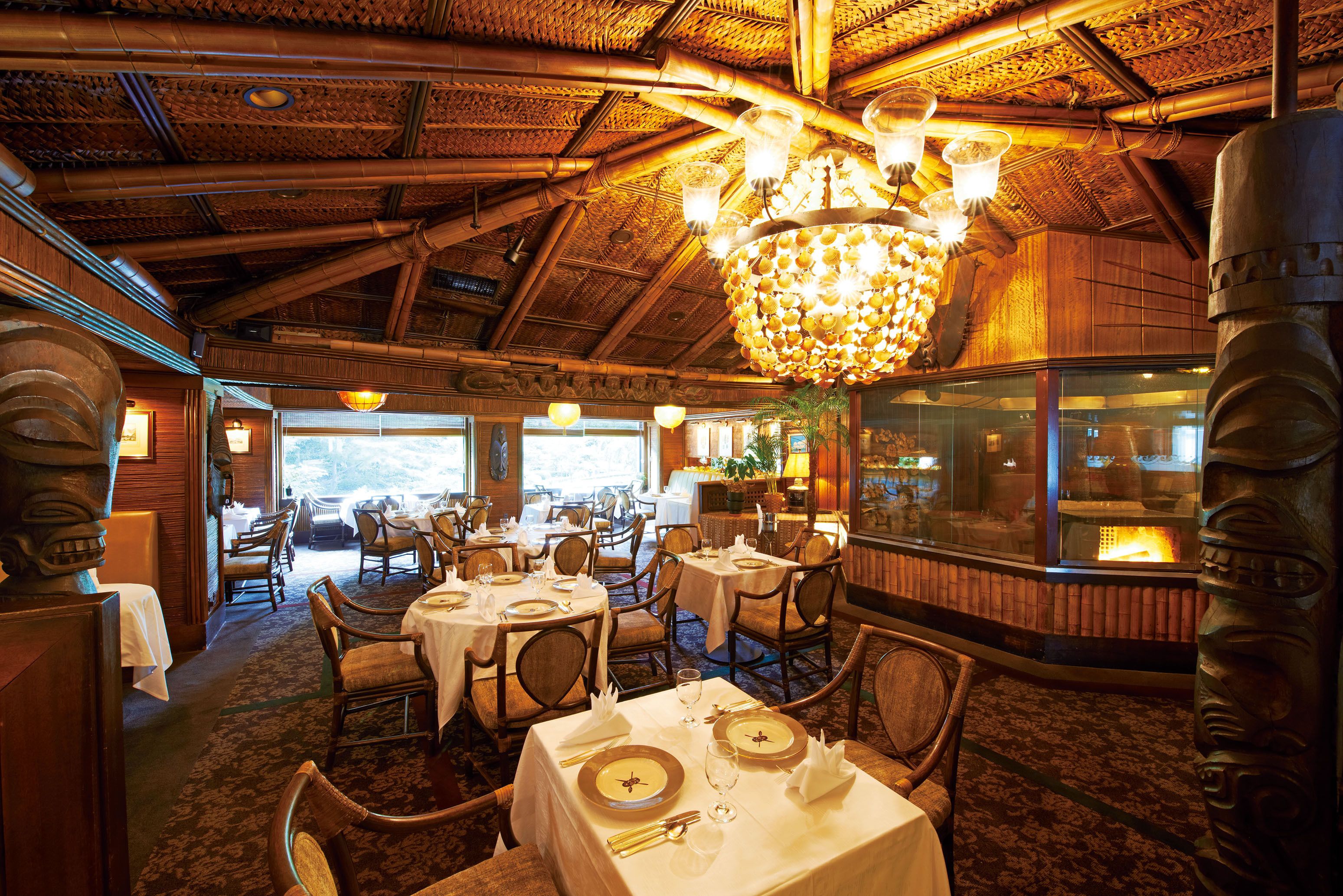 Un restaurant au décor intérieur en bois, avec des tables recouvertes de nappes blanches et un grand lustre.