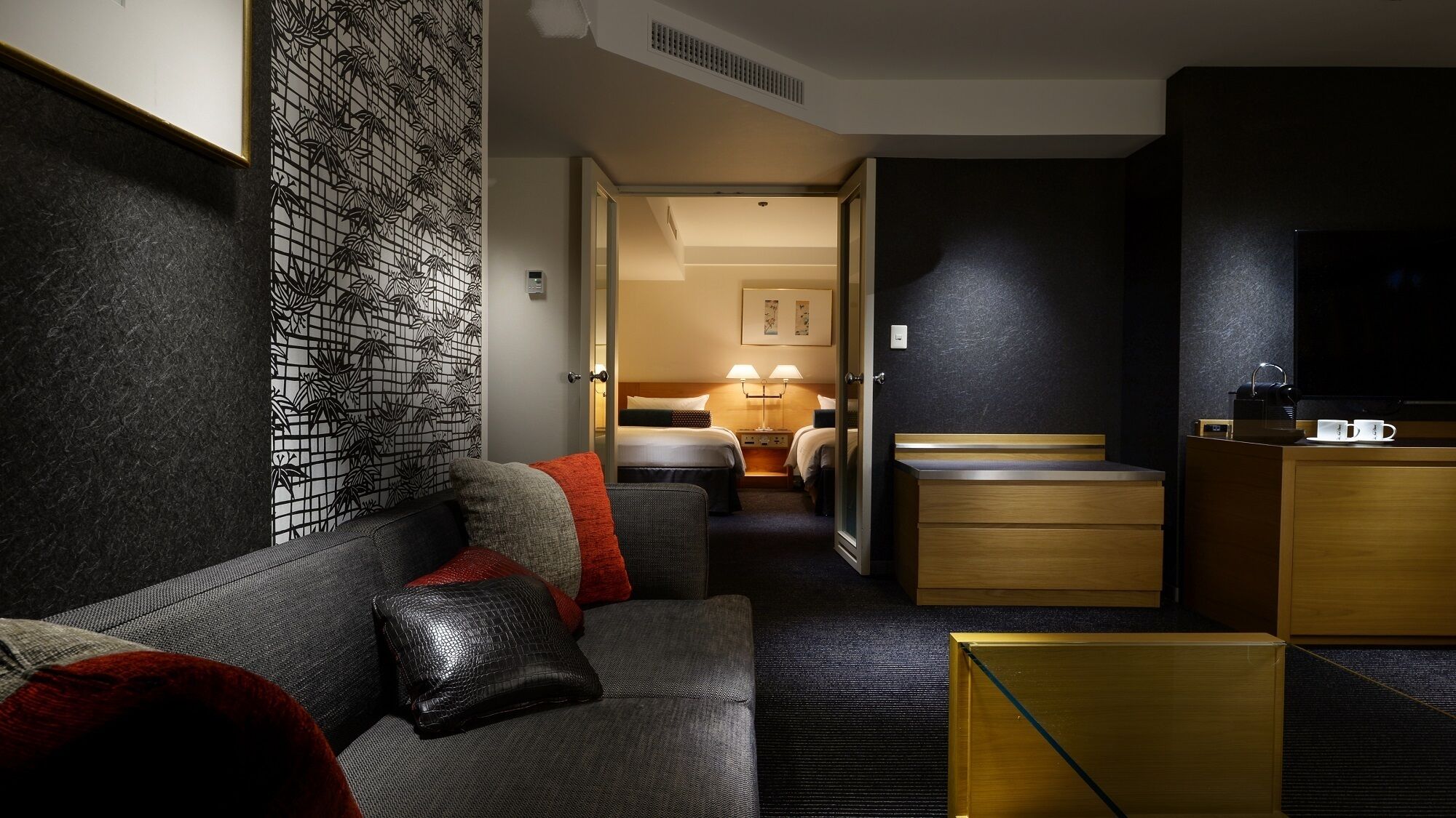 A hotel room with a sofa, a bed, a desk, and a TV.