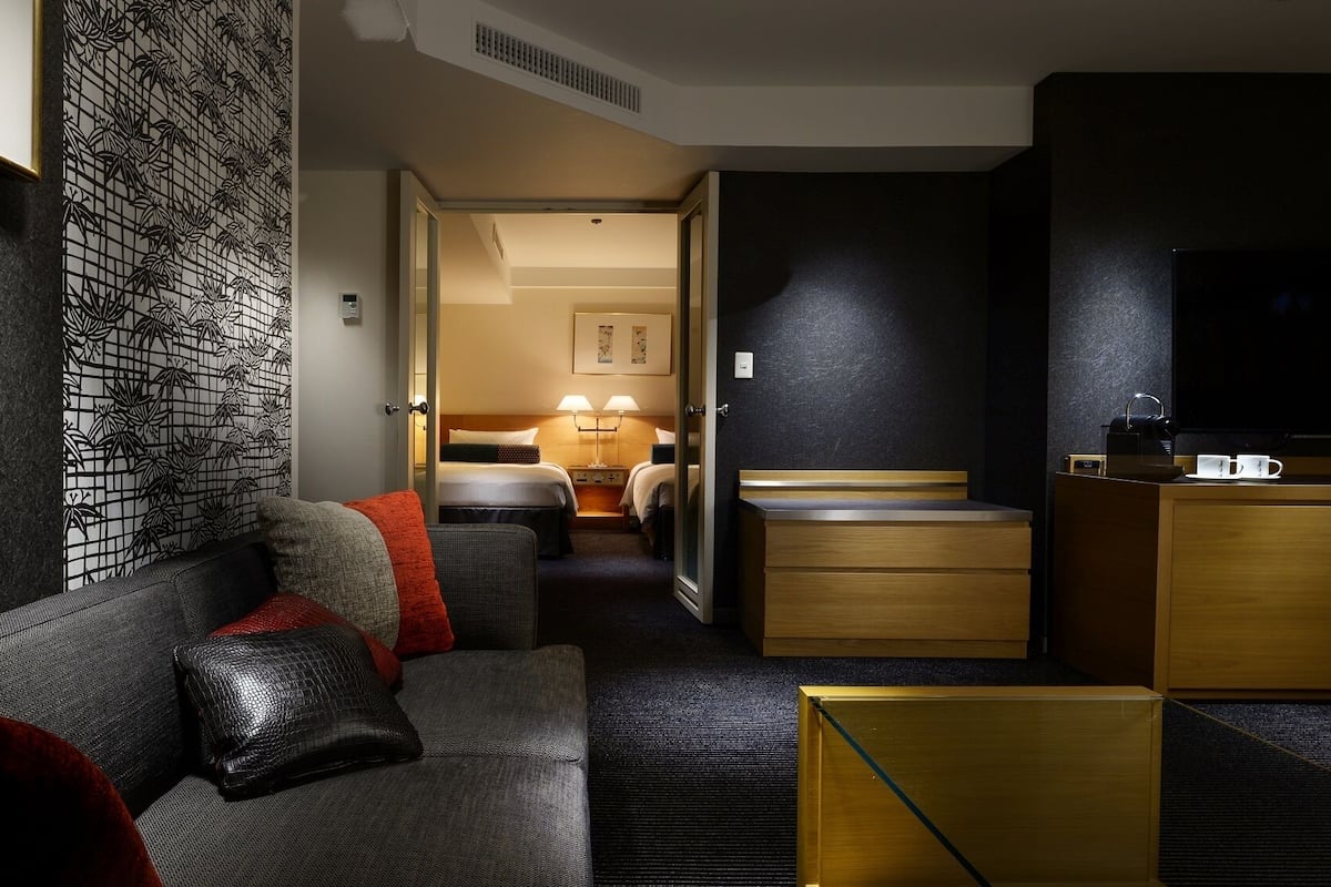 A hotel room with a sofa, a bed, a desk, and a TV.