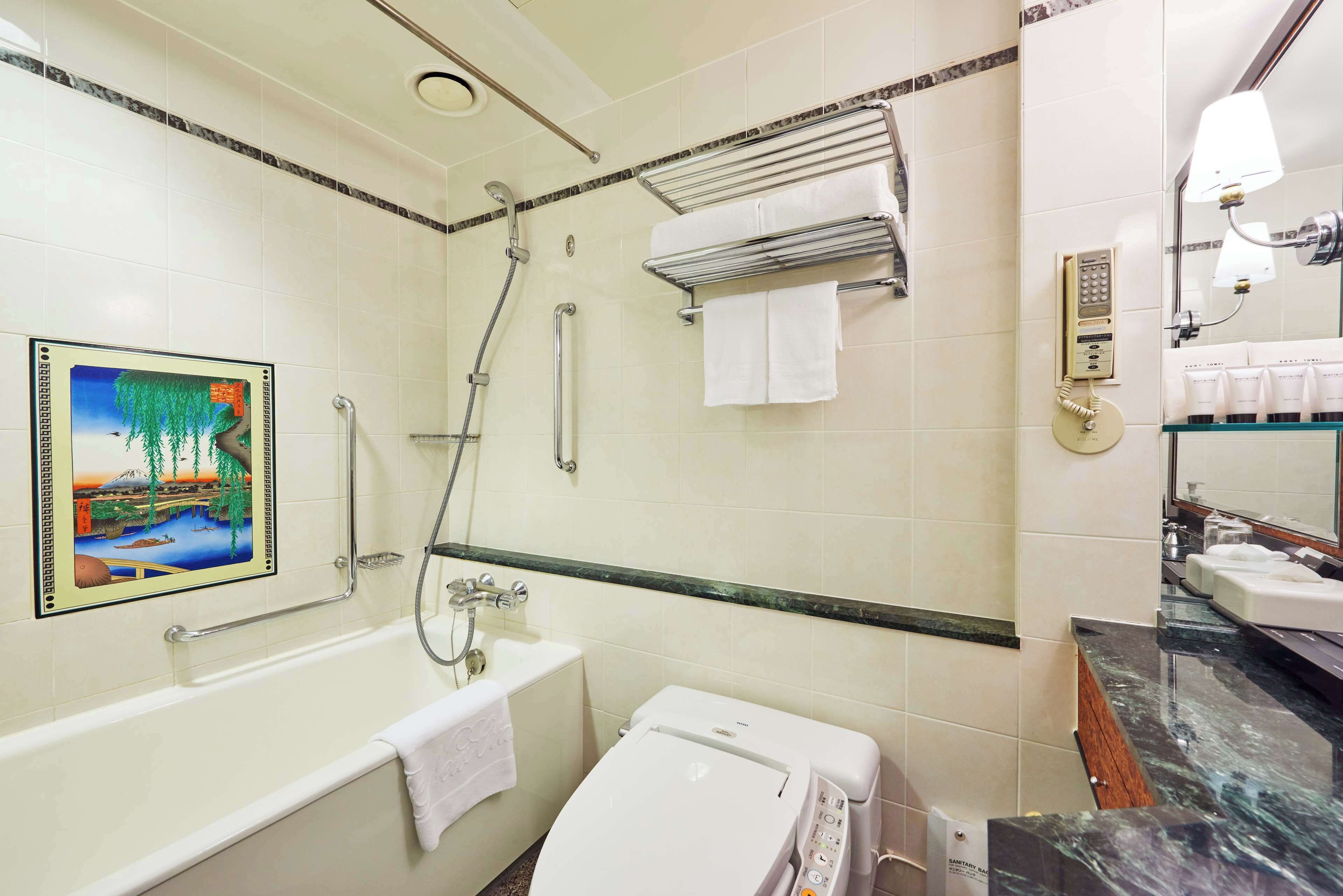 A bathroom with a bathtub, a shower, a toilet, a towel rack, a sink, and a mirror.