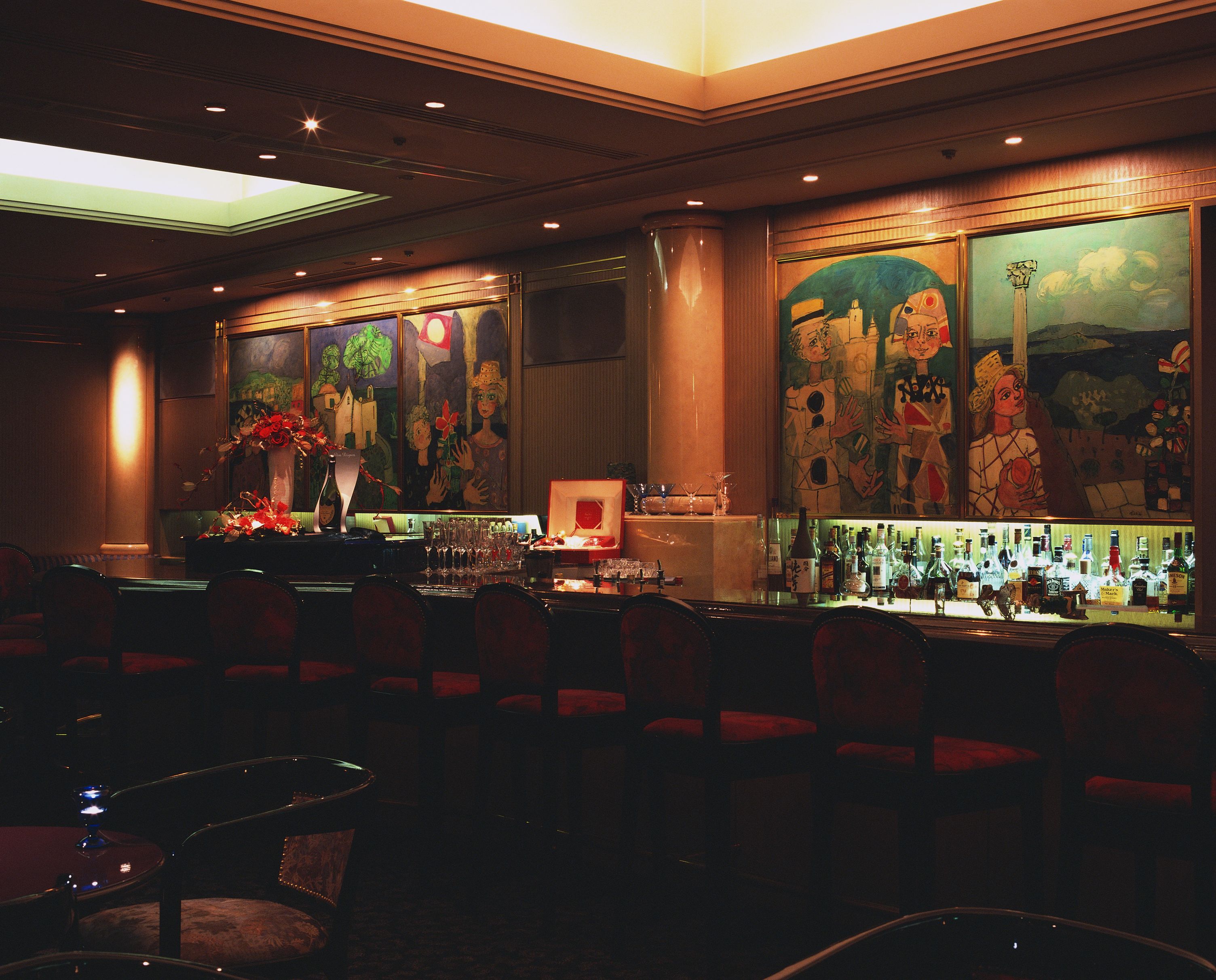 A bar area with a long counter, multiple seating options, and a large mural on the wall.