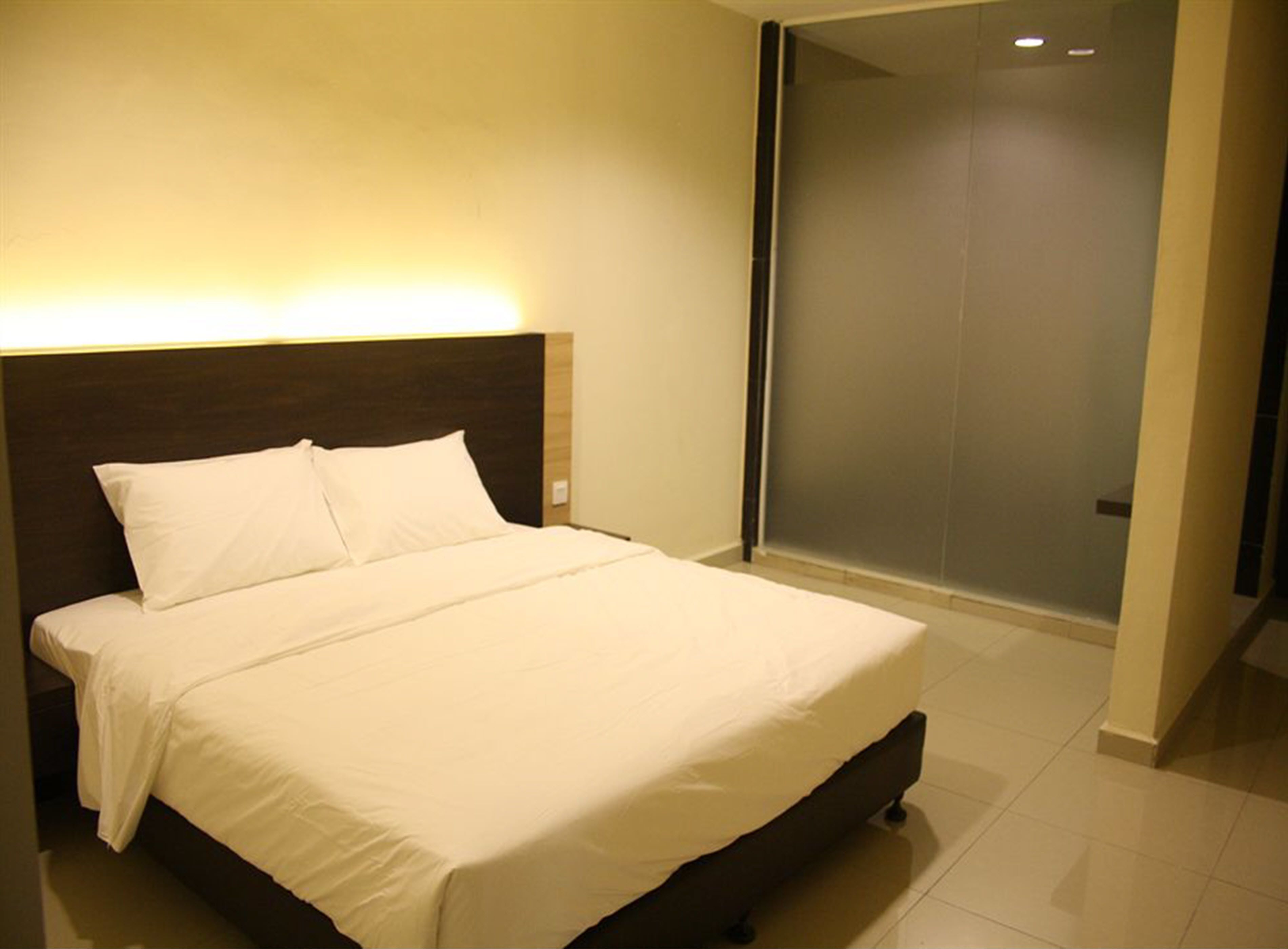 A neatly made bed with white linens in a modern hotel room.