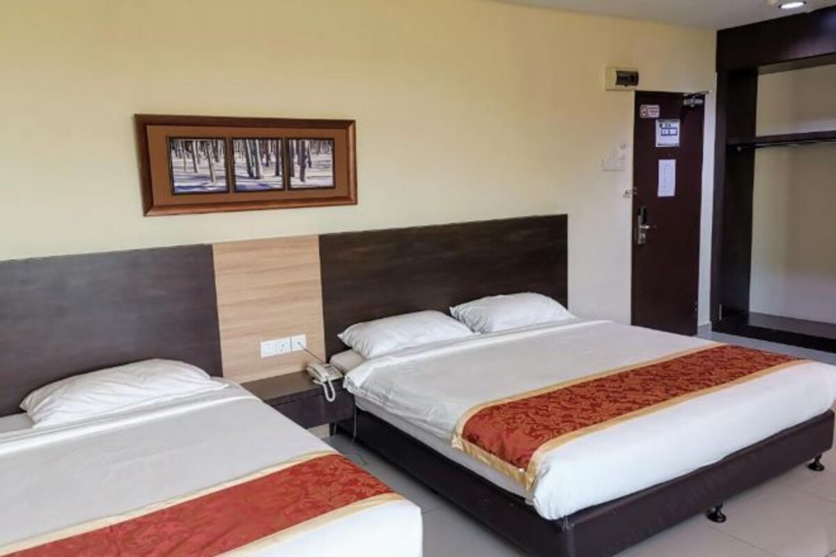 A hotel room with two beds, a wooden headboard, a framed picture on the wall, and a door with a sign.