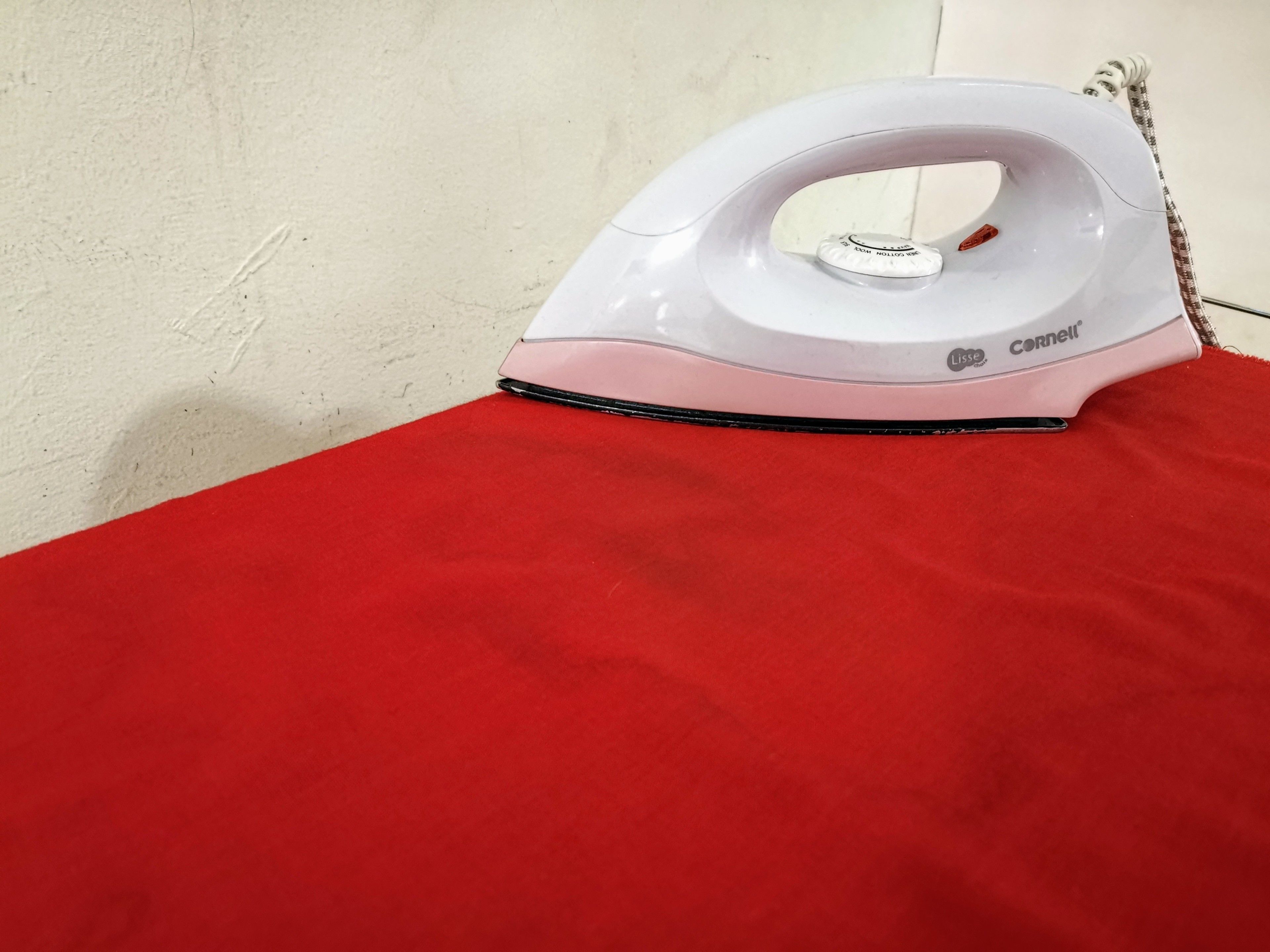 An iron on a red surface.