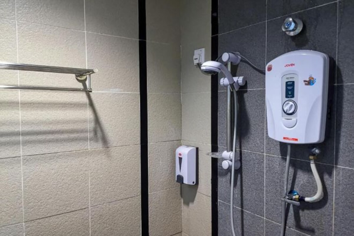 A modern bathroom with a shower, a hand dryer, and a water heater.