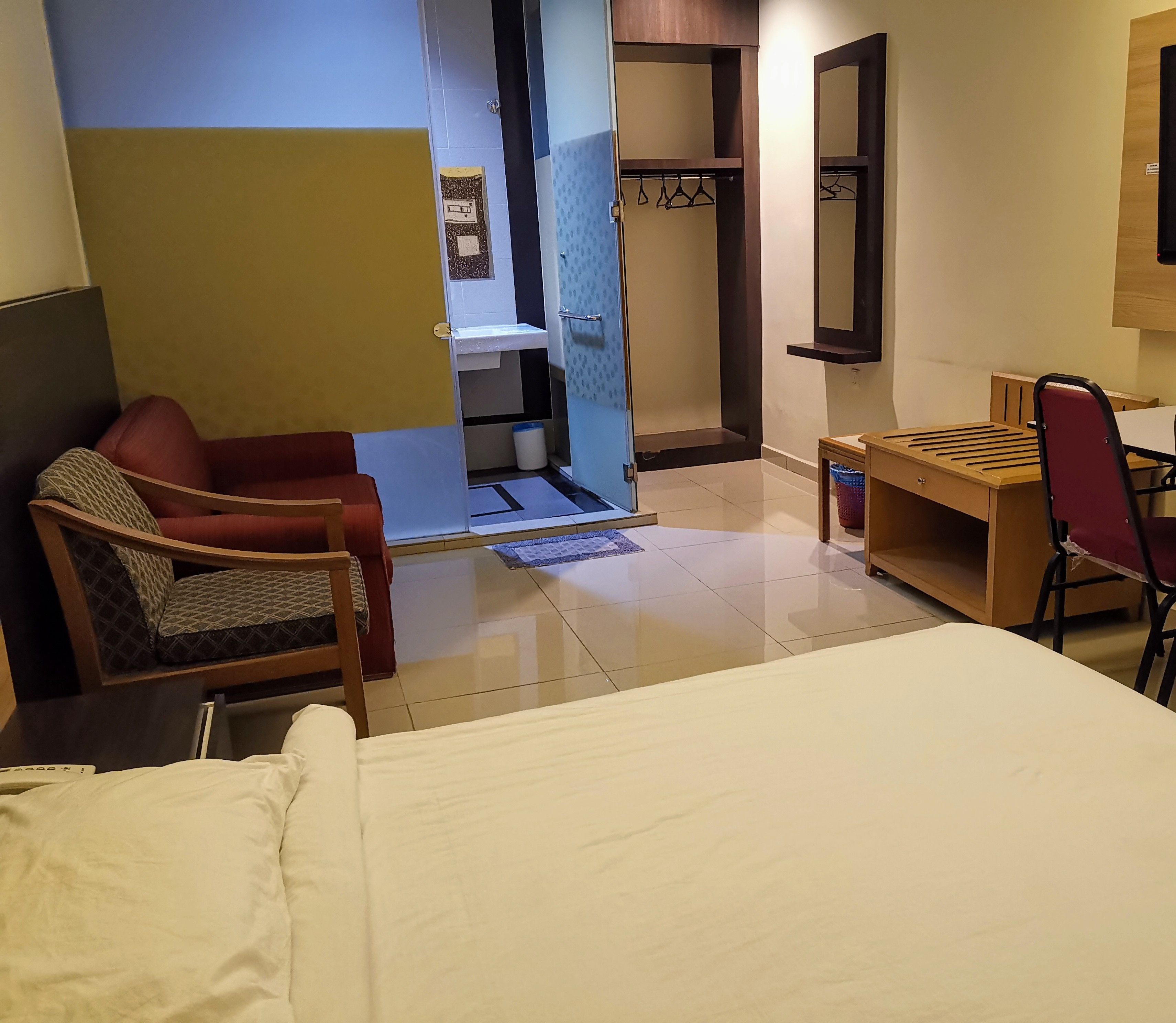 Une chambre d’hôtel comprenant un lit, un bureau, une chaise, une armoire et une salle de bain.