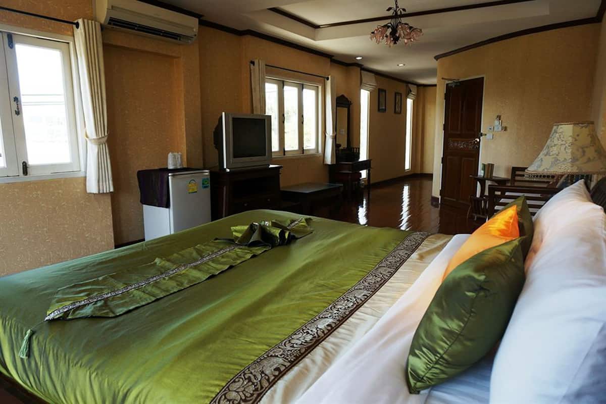 Quarto de hotel com uma cama grande, televisão, escrivaninha e uma cadeira.
