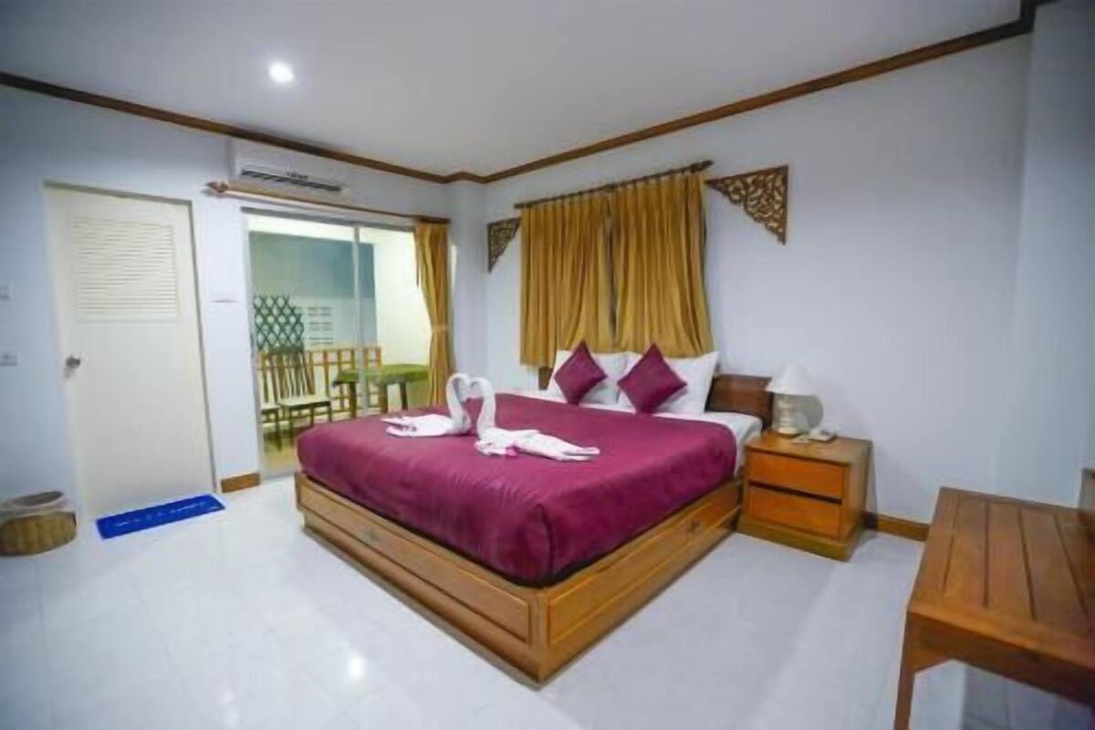 Quarto com cama, mesa de cabeceira e uma pequena mesa de madeira.