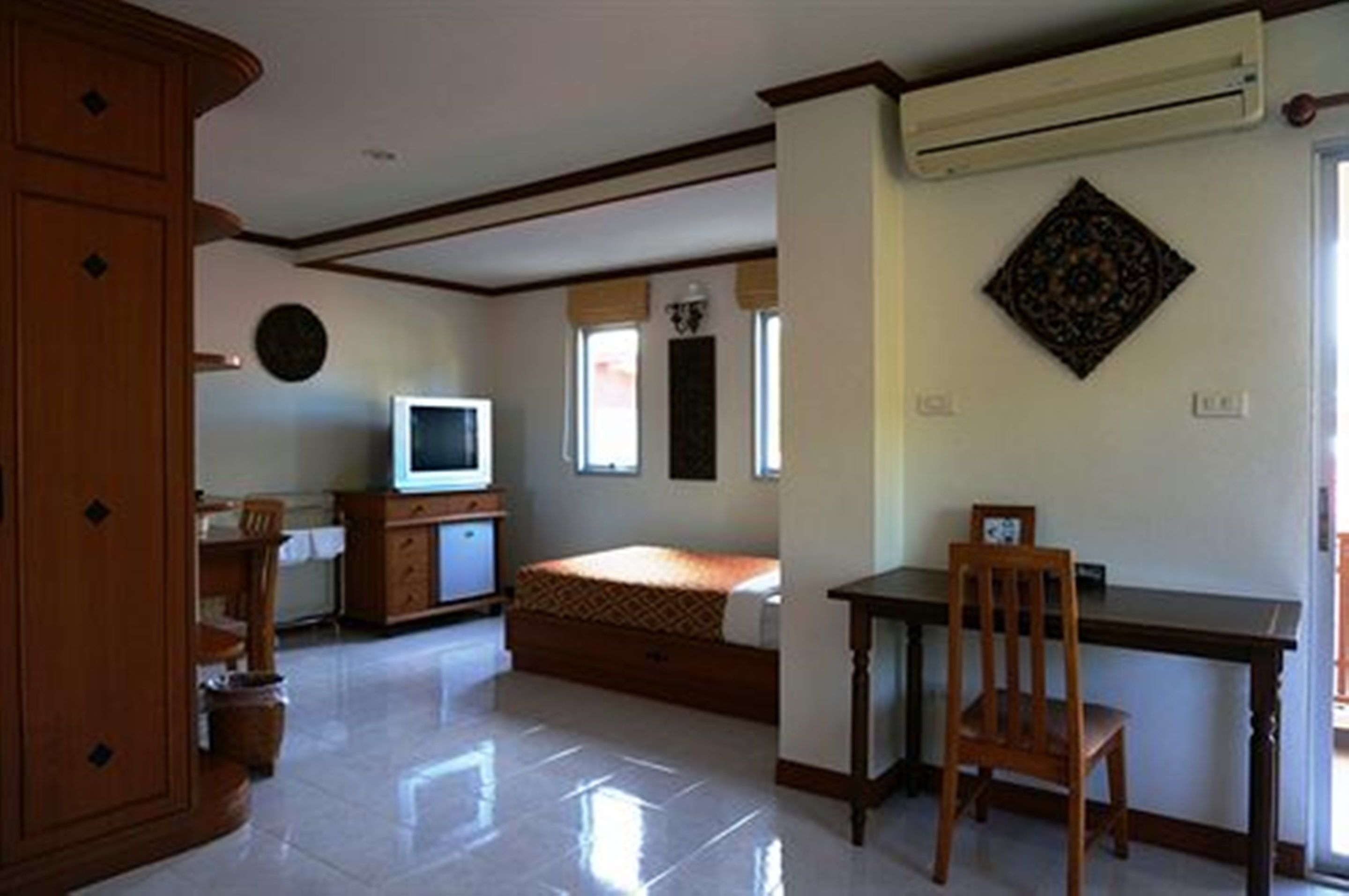 Una habitación con cama, escritorio, silla, televisor y armario.
