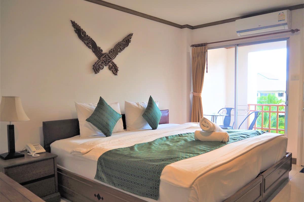 Cama bem arrumada com colcha estampada, telefone ao lado e almofadas decorativas.