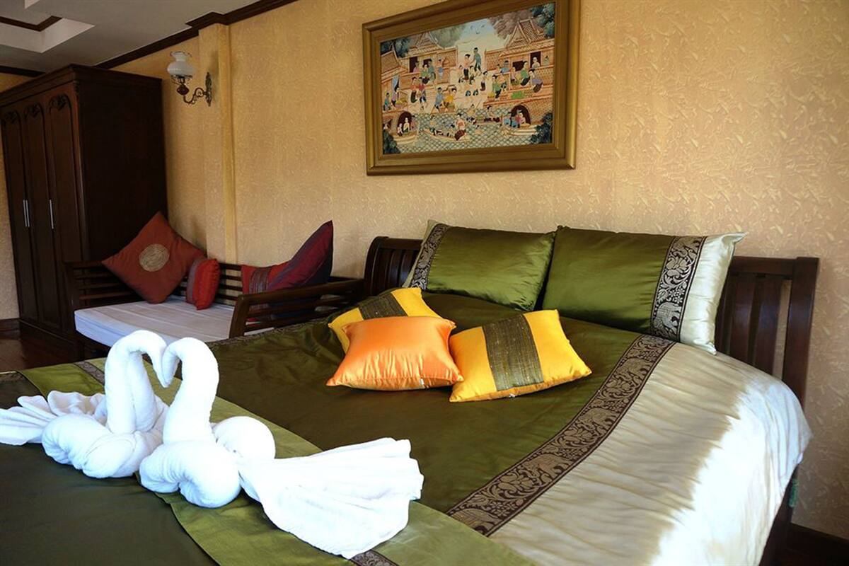 Quarto de hotel com cama, almofadas, pintura na parede e um guarda-roupa.