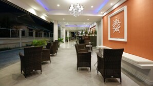 Eine Hotelhalle mit Korbmöbeln, einer Chandelüster und einem dekorativen Wandbild.