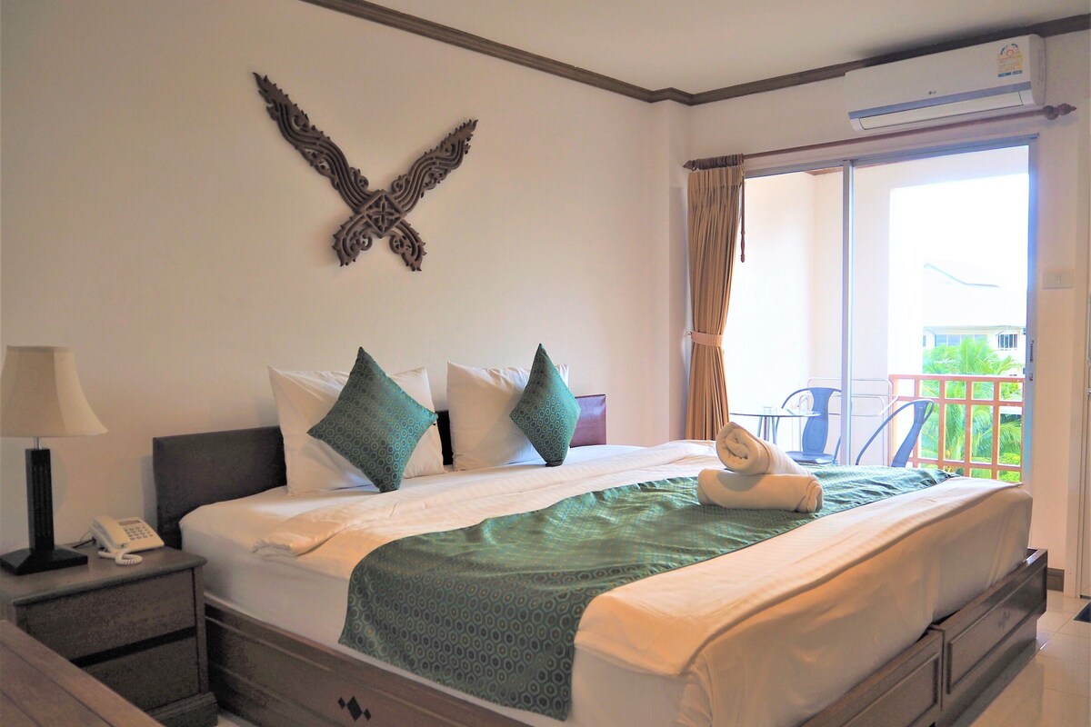 Une chambre d’hôtel avec un grand lit, un téléphone sur la table de chevet, un élément décoratif mural et un balcon avec vue.