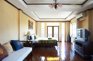 Una habitación de hotel con cama, sofá, televisión y candelabro.