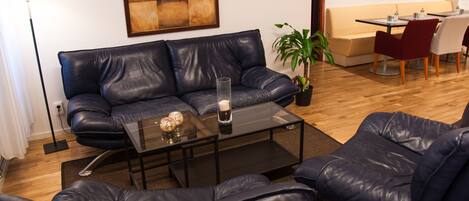 Una sala de estar moderna con un sofá de cuero, una mesa de centro de vidrio y un comedor con una mesa y sillas.