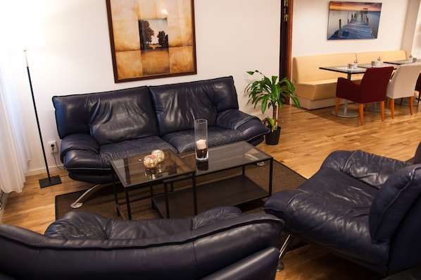 A modern living room with a leather sofa, a glass coffee table, and a dining area with a table and chairs.