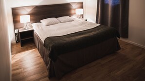 Un letto rifatto con cura, con una testiera scura e due lampade ai comodini.