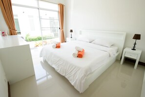 A hotel room with a large bed, white bedding, two nightstands, and a view of greenery outside. - Talay Tara Resort (Sam Roi Yot)