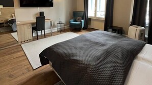 Une chambre d’hôtel moderne, dotée d’un grand lit, d’un bureau, d’une chaise, d’une télévision et d’une fenêtre avec des rideaux.