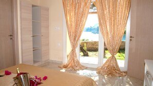 Un dormitorio con cama, un minibar y vistas a una pared de piedra y follaje exterior.