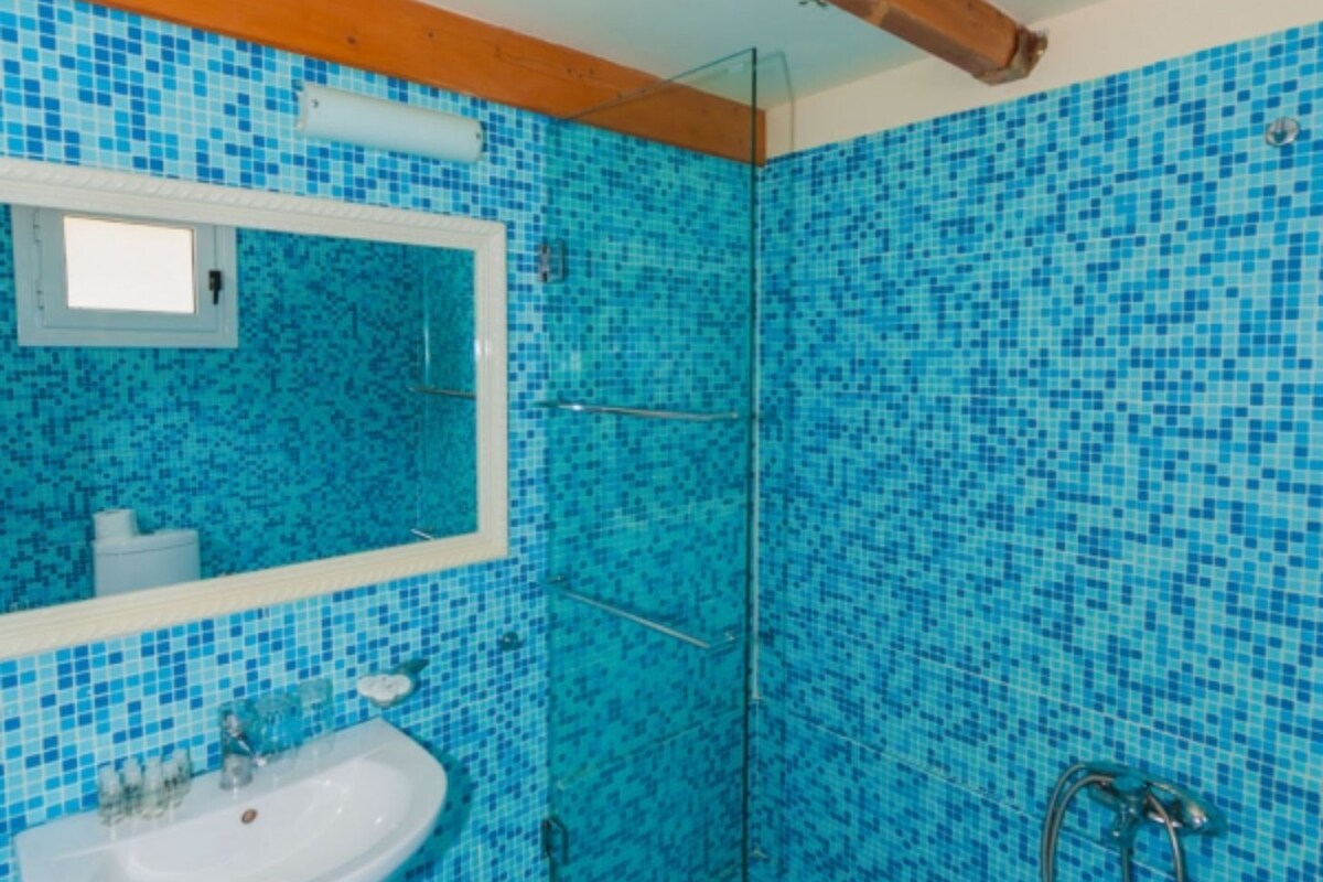 A bathroom with a sink, mirror, and shower area.