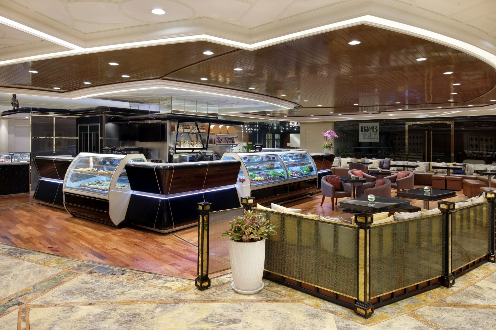 A modern restaurant with a glass display case, seating area, and a decorative plant.