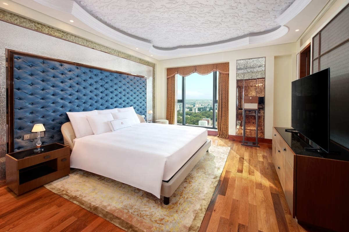 Un dormitorio con una cama grande, televisión y vistas a la ciudad.