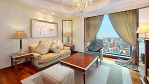 Un salon spacieux avec vue sur la ville, un lustre, un ensemble de canapés et une table basse.