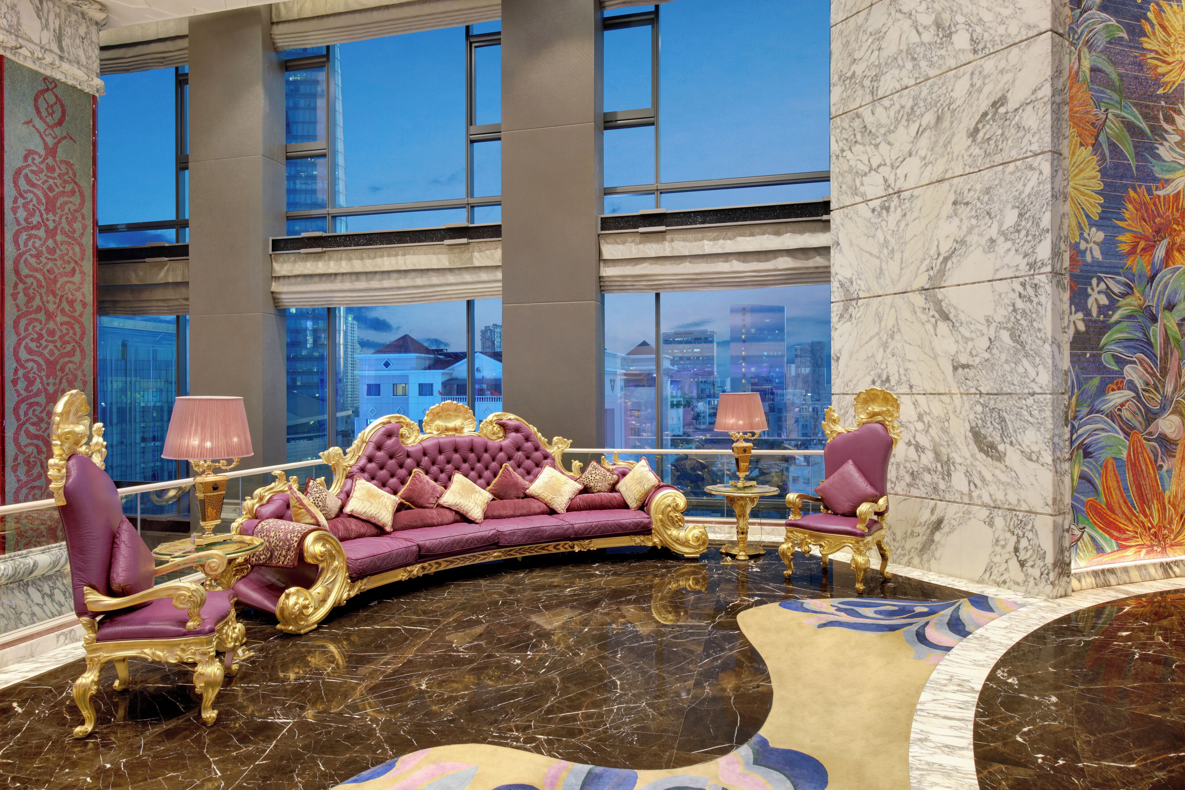 Eine luxuriöse Lobby mit einer bequemen, violetten Couch, goldfarbenen Sesseln und einem Marmorboden.