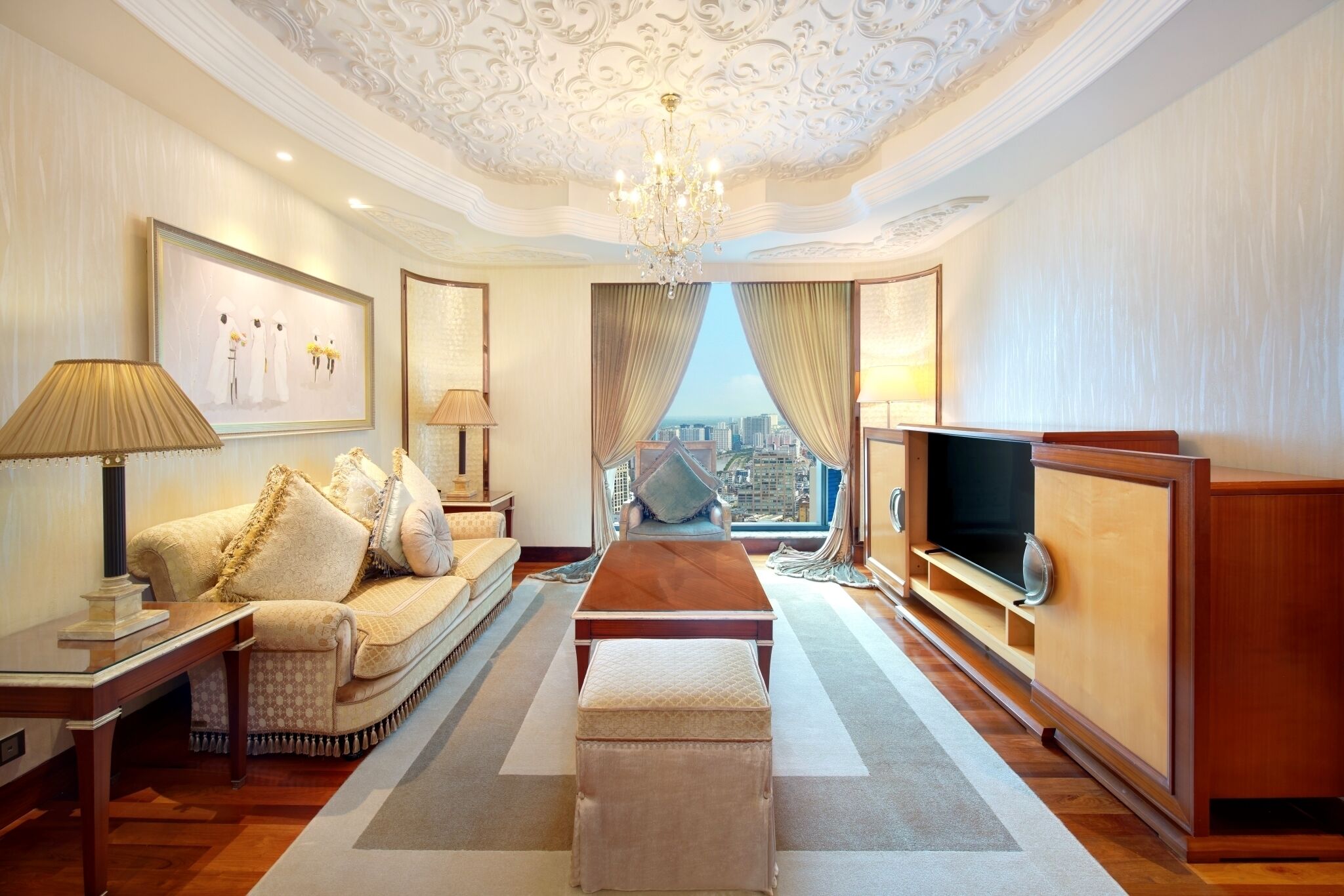 Amplia habitación de hotel con una cama grande, televisión, sofá y vistas a la ciudad.