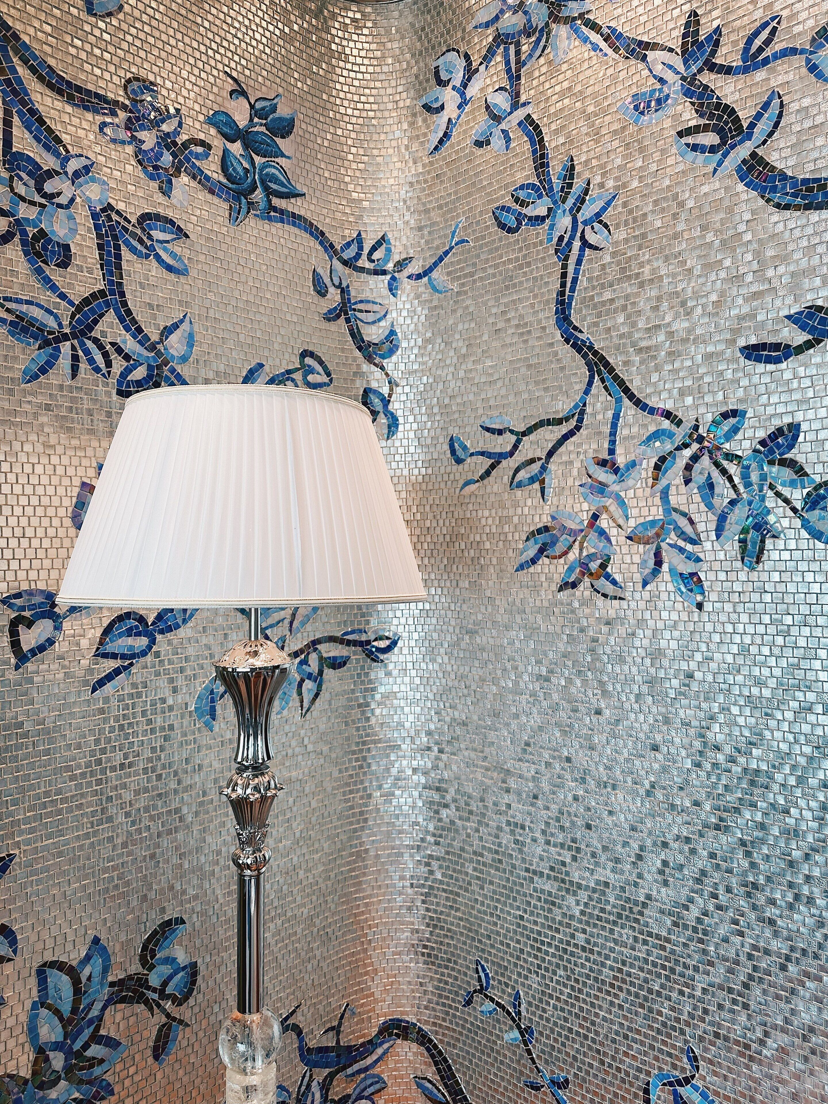 A room with a lamp and a wall decorated with blue and black mosaic tiles.
