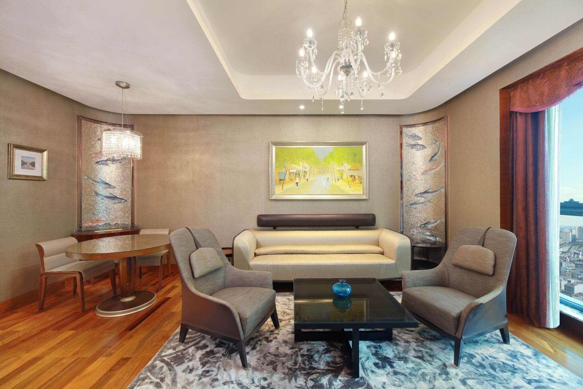 A modern living room with a round dining table, two armchairs, a sofa, and a chandelier.