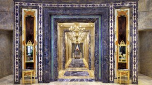 Ein prachtvoller Korridor mit aufwendiger Dekoration, einem Chandelier und einem Marmorboden.