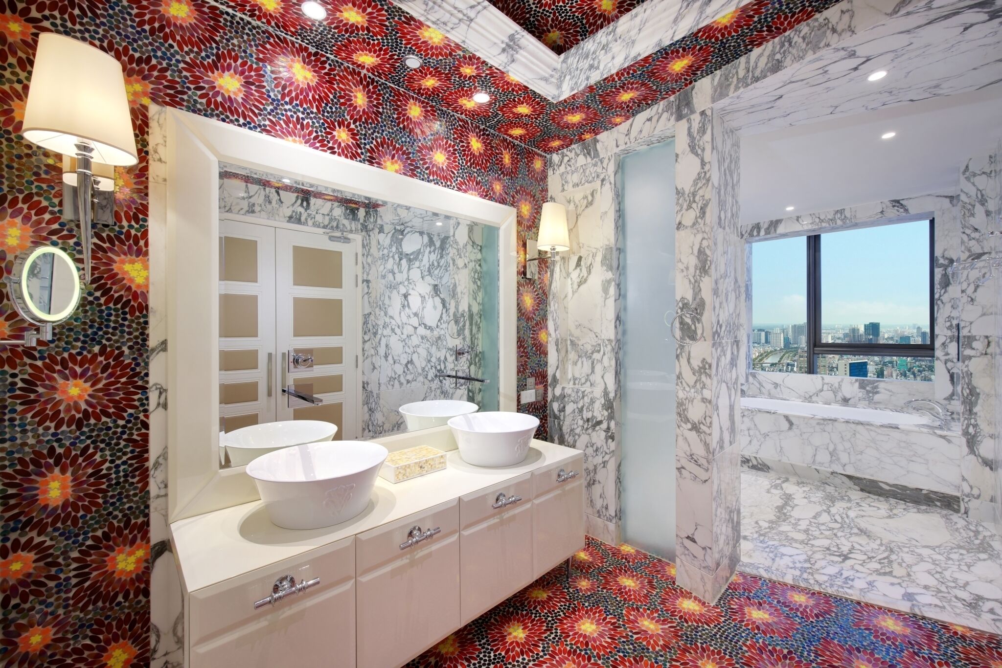A bathroom with a large mirror, three sinks, and a bathtub. The walls have a marble-like pattern, and the floor has a colorful floral design.