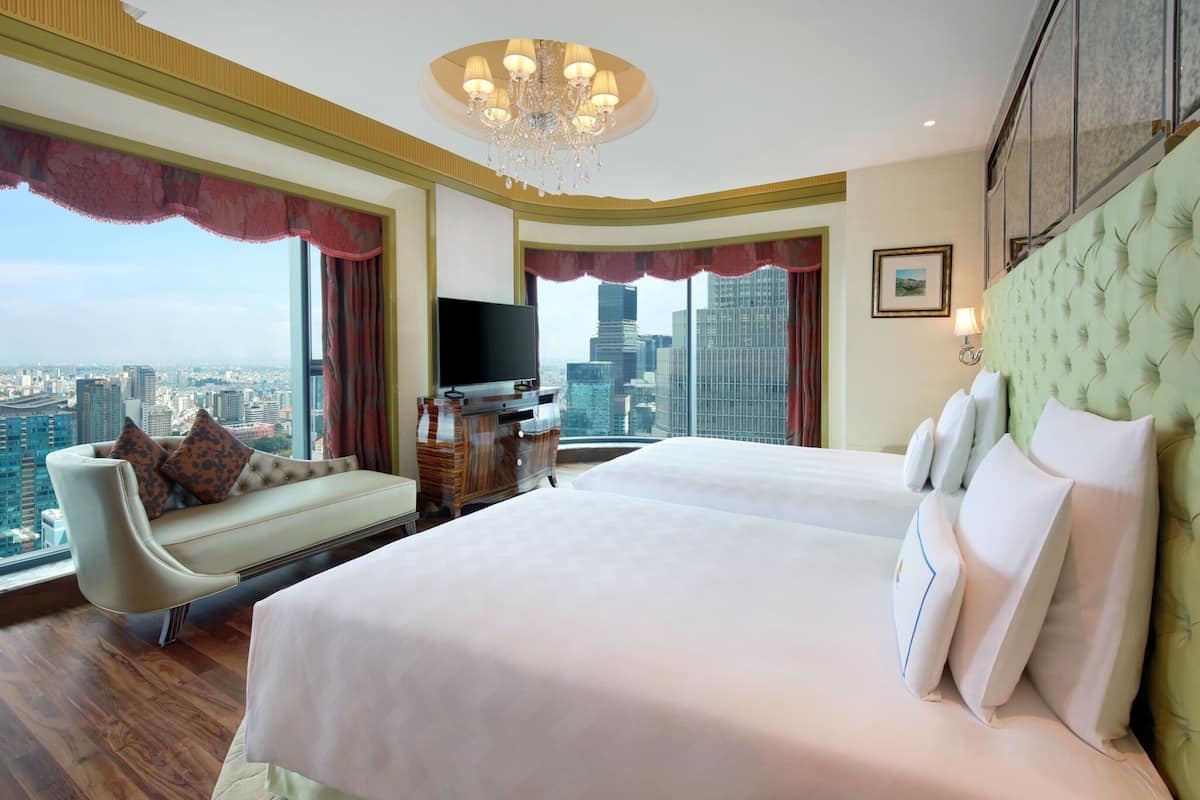 Habitación de hotel con una cama grande, un sofá, un televisor y vistas a la ciudad.