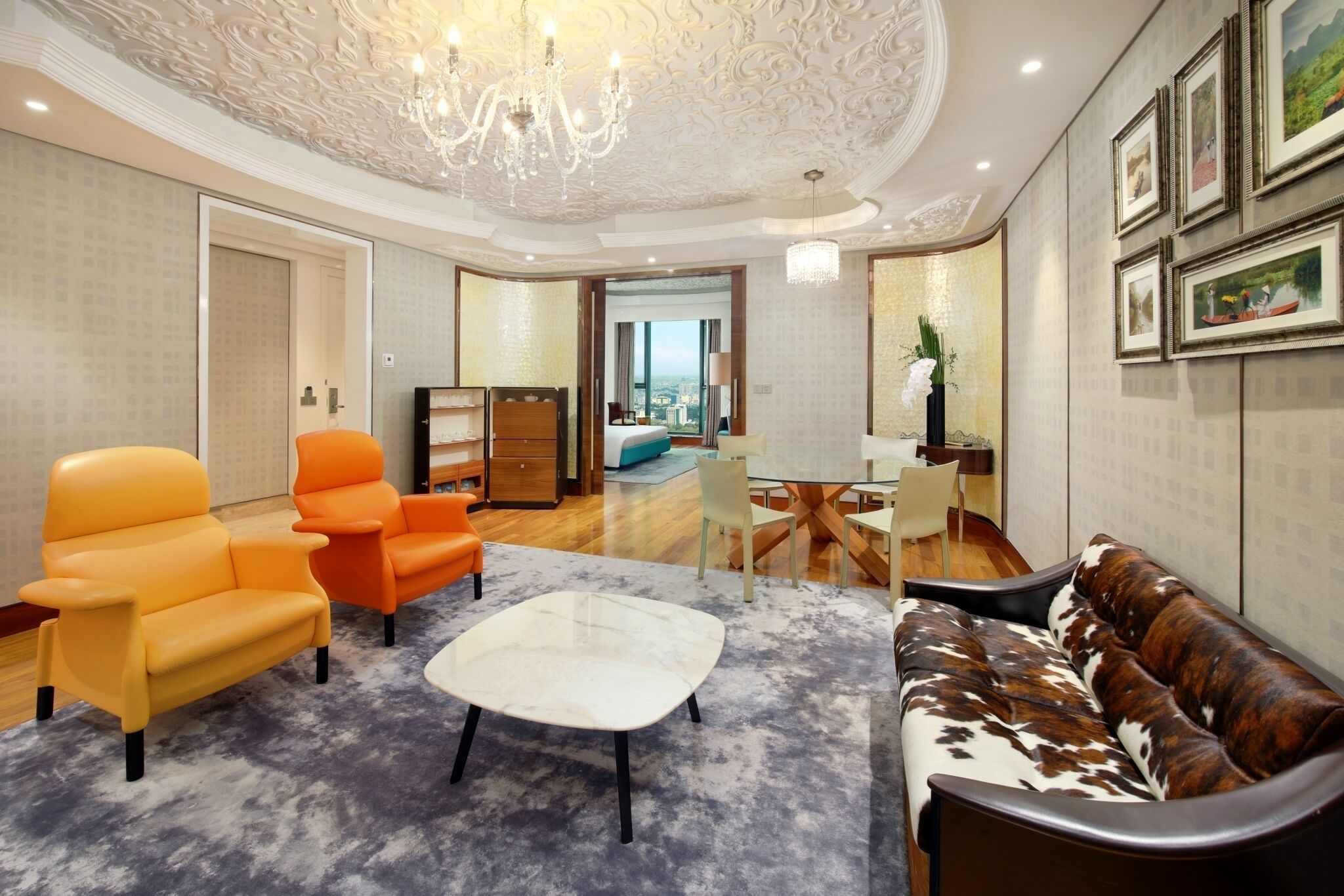 A modern living room with a chandelier, a sofa, armchairs, and a coffee table.