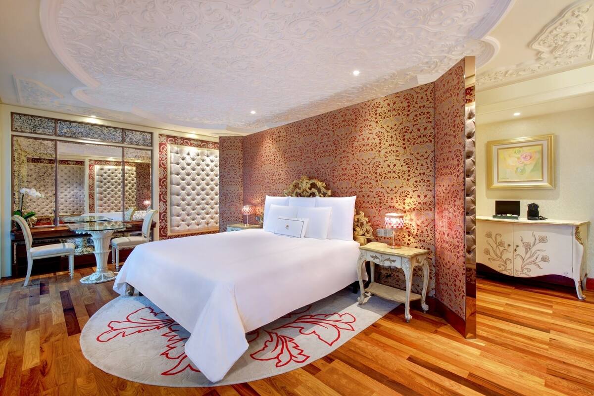 Un dormitorio con una cama grande, un tocador, un espejo y un escritorio con una silla.