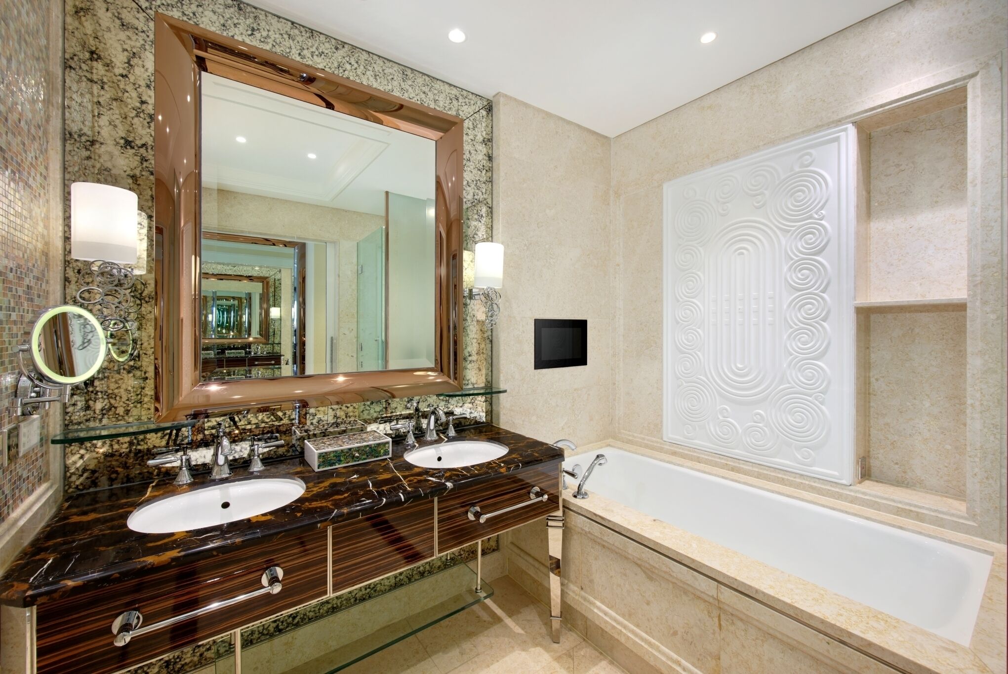 A bathroom with a double sink vanity, a large mirror, a bathtub, and a decorative wall panel.