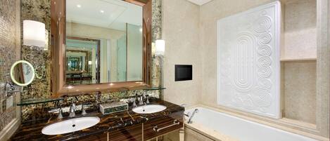 A bathroom with a double sink vanity, a large mirror, a bathtub, and a decorative wall panel.