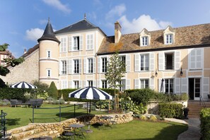 A historic building with a courtyard featuring outdoor seating and a stone wall. - The Originals Relais, Hôtel St Laurent (Montfort-l'Amaury)