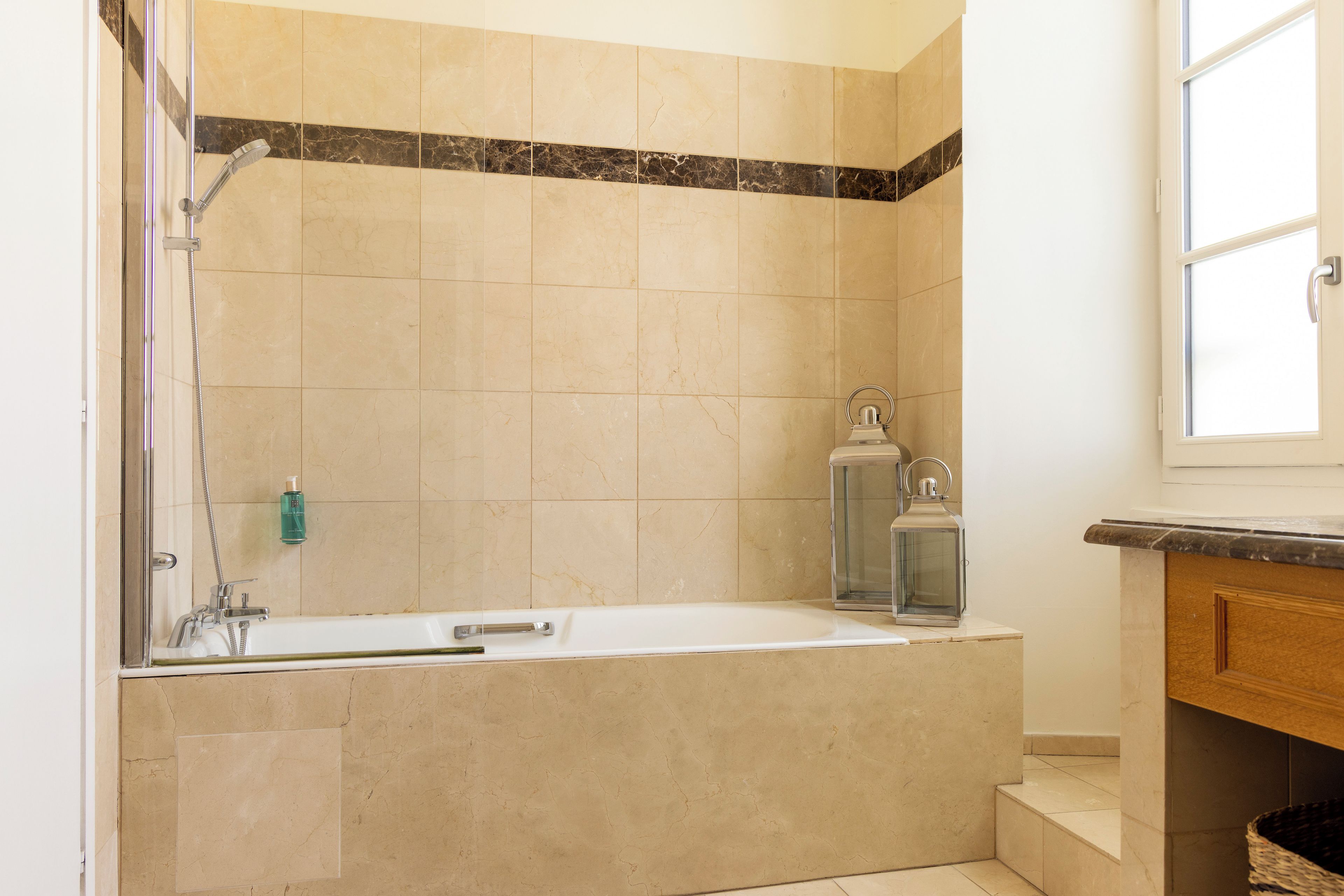 A bathroom with a bathtub, shower, and a window.