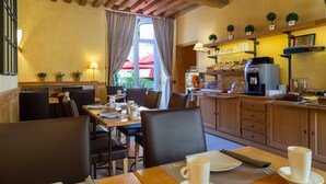 Un accogliente ristorante con travi in legno, un'area pranzo con tavoli e sedie e una cucina con scaffali ed elettrodomestici.